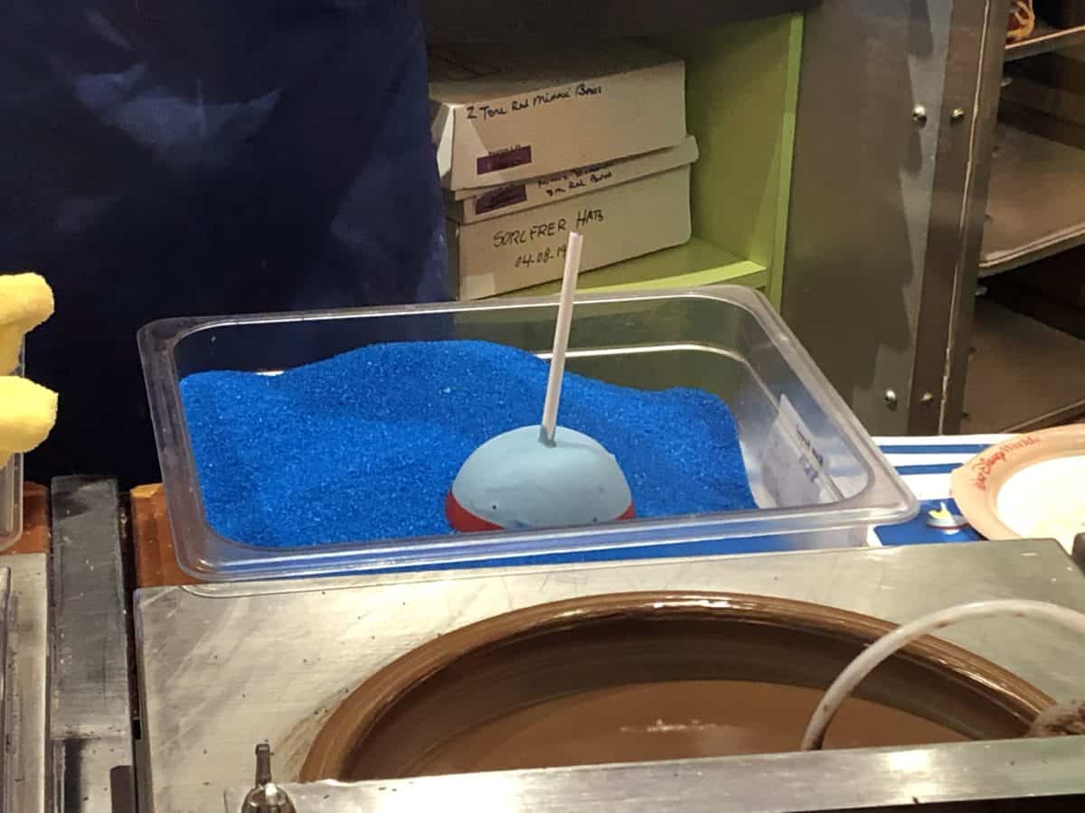 Genie caramel apple in a container of bright blue sugar springs