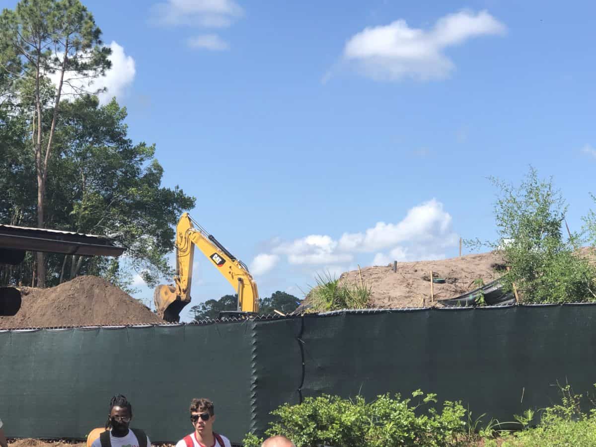 Trees are gone, a mound of dirt and construction equipment is barely visible over the fence
