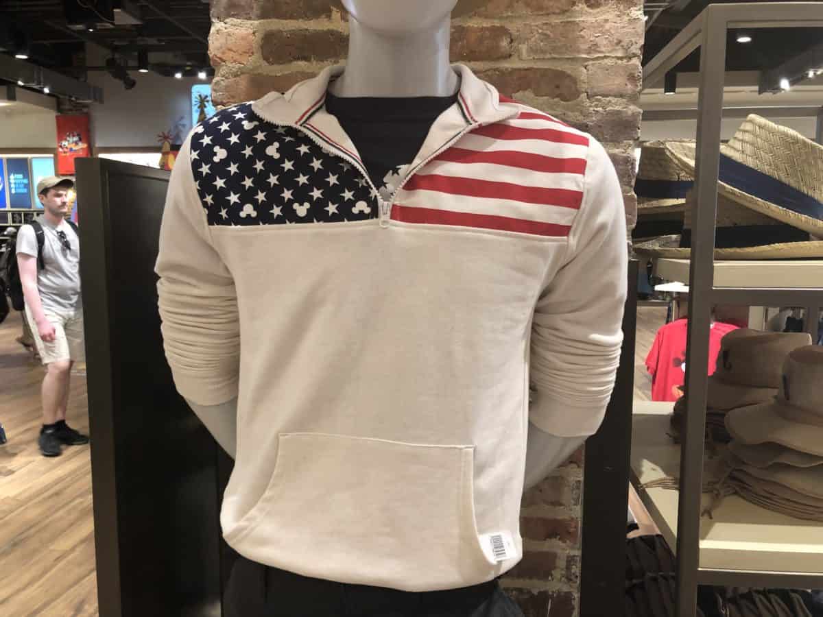 White colored half-zip sweater with stripes on one shoulder, and stars and Mickey heads on the other shoulder