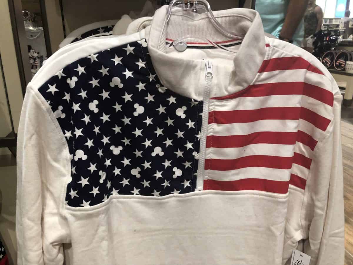 White colored half-zip sweater with stripes on one shoulder, and stars and Mickey heads on the other shoulder