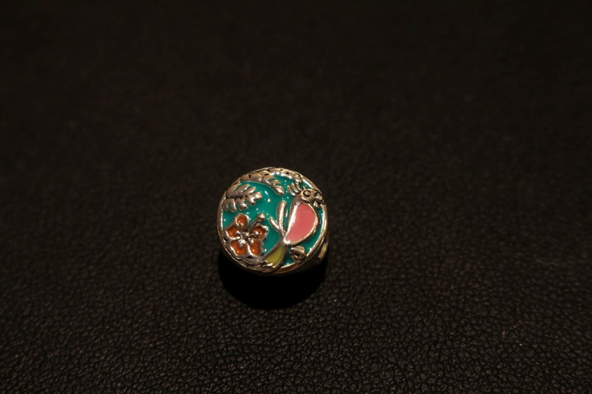 Silver bead style charm with teal background, and pink and red bird and hibiscus