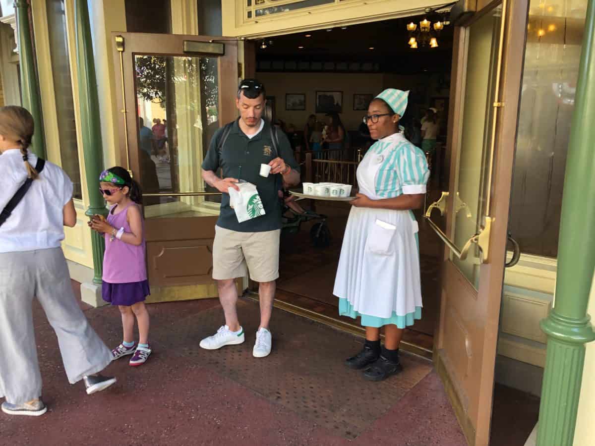 Main Street Bakery Cast Member holding a tray of cups with cinammon roll samples