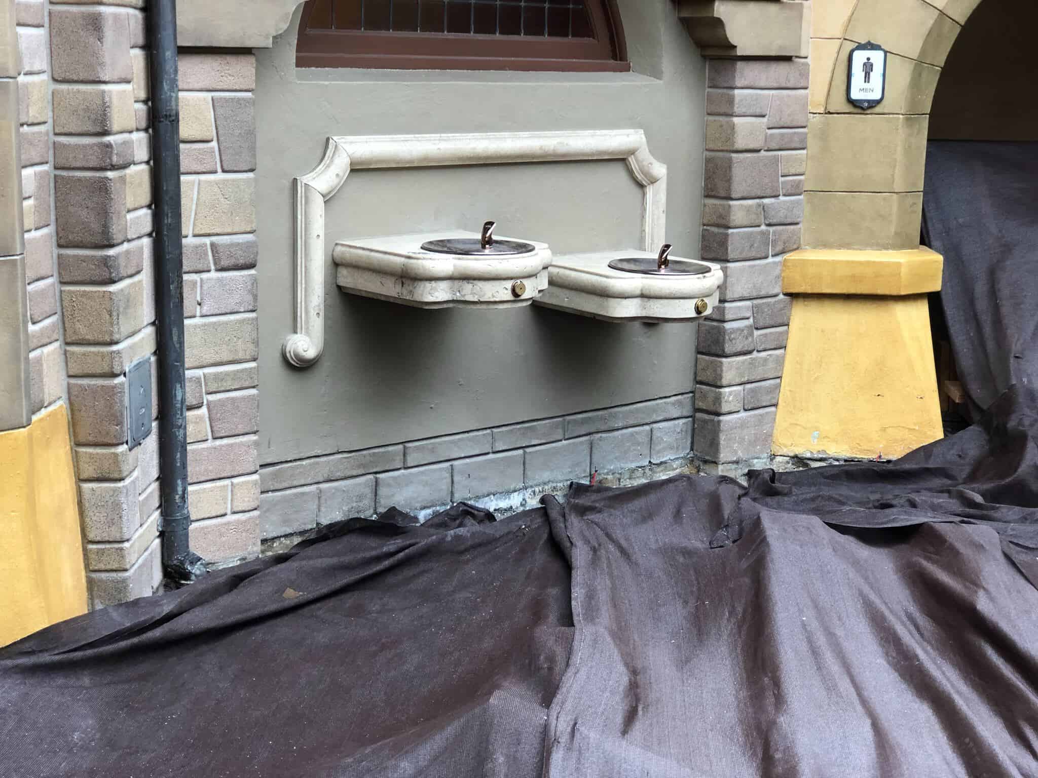 Construction on the ground around the water fountains outside Fantasyland restrooms
