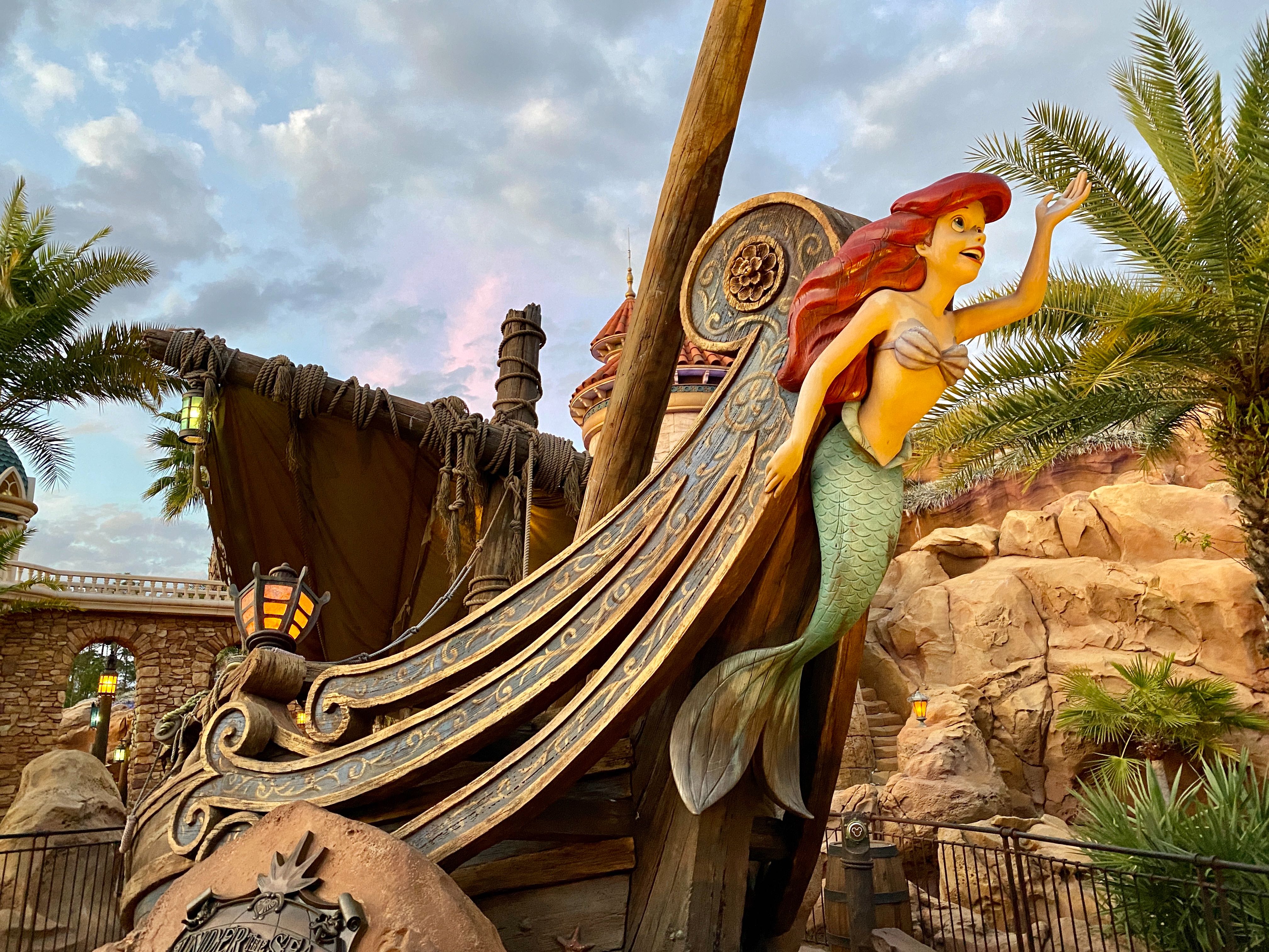 A sculpture of Ariel from the Little Mermaid on the front of a beached ship, which serves as the entrance to Under the Sea – Journey of the Little Mermaid at Magic Kingdom.