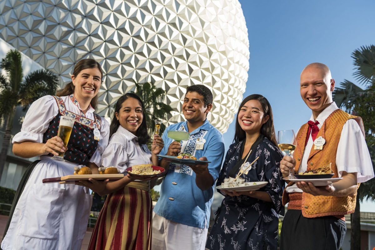 EPCOT World Showcase Cast Members in a variety of costumes in front of Spaceship Earth