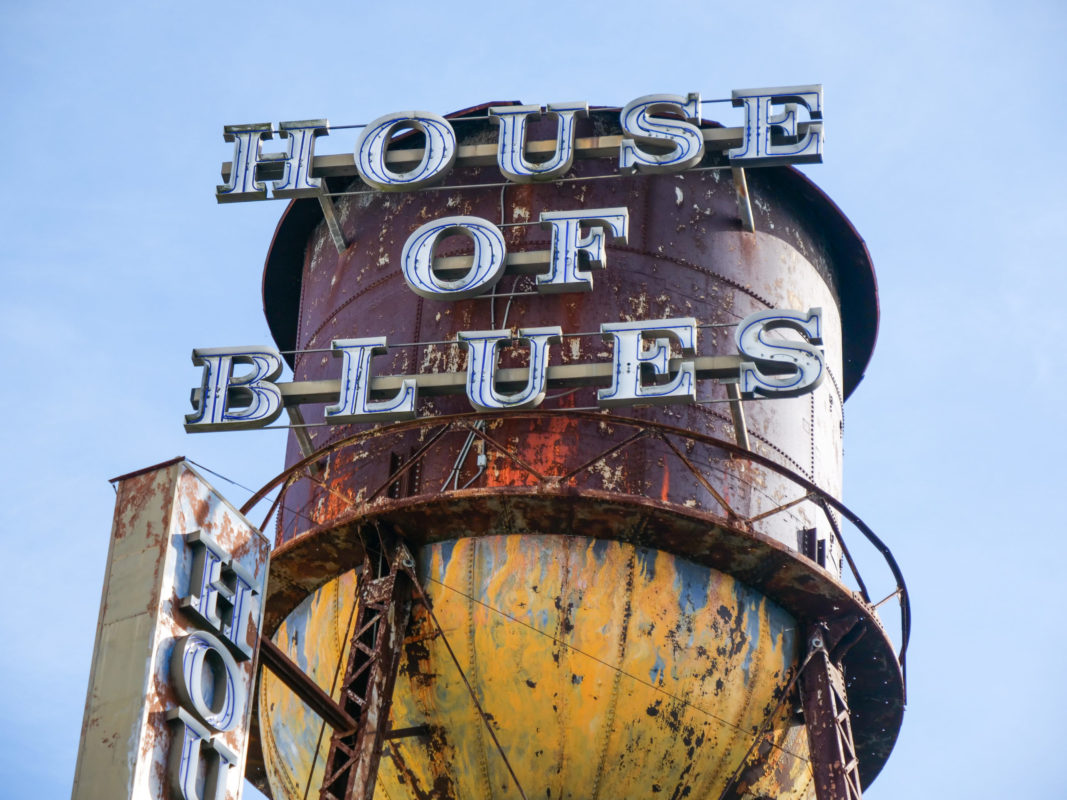 The rusty water tower, adorned with metal letters spelling "House of Blues," stands proudly against a clear blue sky, hinting at the history and charm that awaits inside. Catch a glimpse of nostalgia and inquire within about any available House of Blues discount for your visit.