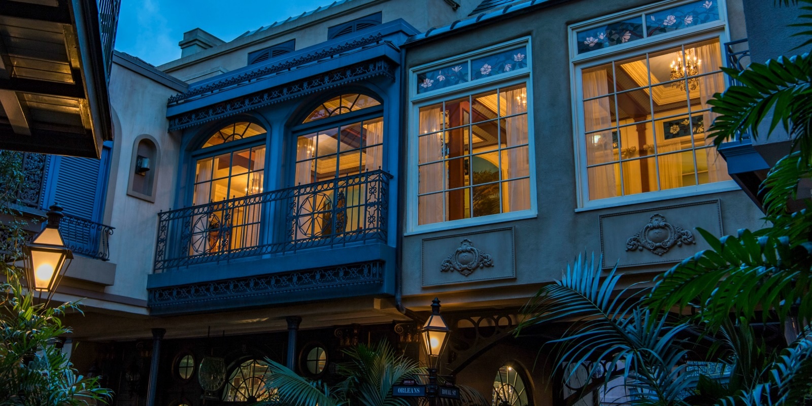 Exterior of Club 33 at Disneyland, with orange light shining through windows at dusk