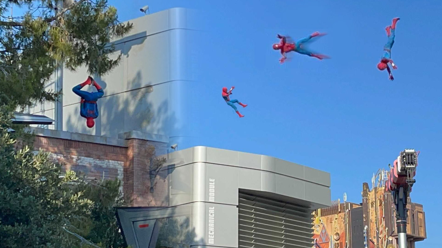 Aerial stunt sequence with Spider-Man figures performing flips beside a modern building. Trees are in the foreground, capturing the thrill of a Spider-Man stunt show.