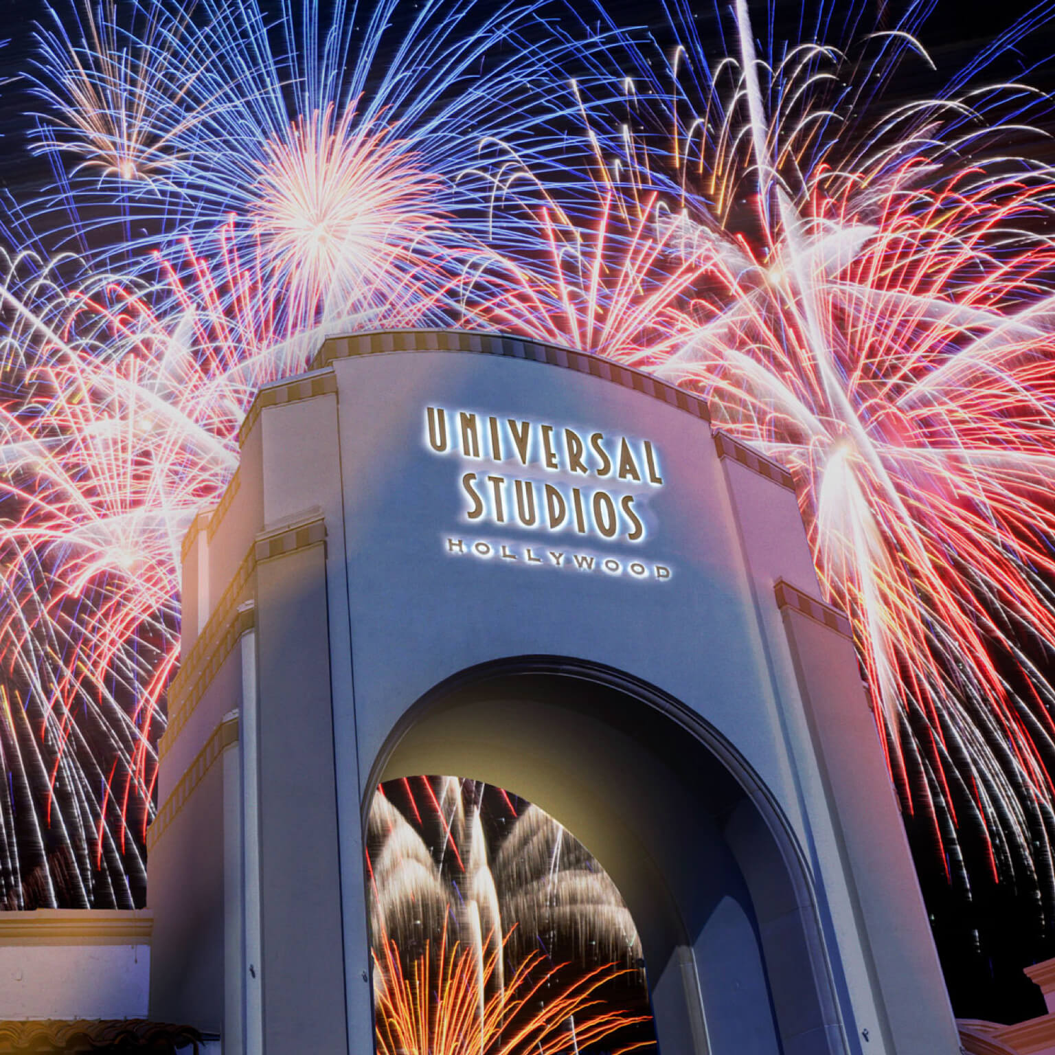 The entrance of Universal Studios Hollywood dazzles with a vibrant fireworks display lighting up the night sky, reminiscent of a spectacular Fourth of July celebration.