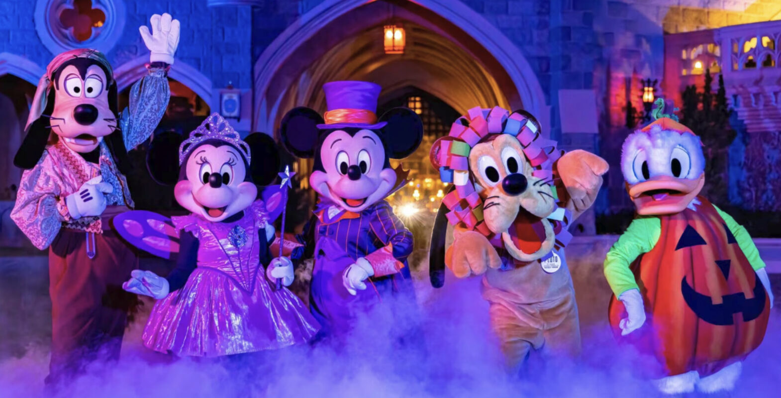 Five Disney characters in Halloween costumes pose together indoors with purple lighting and fog effects.