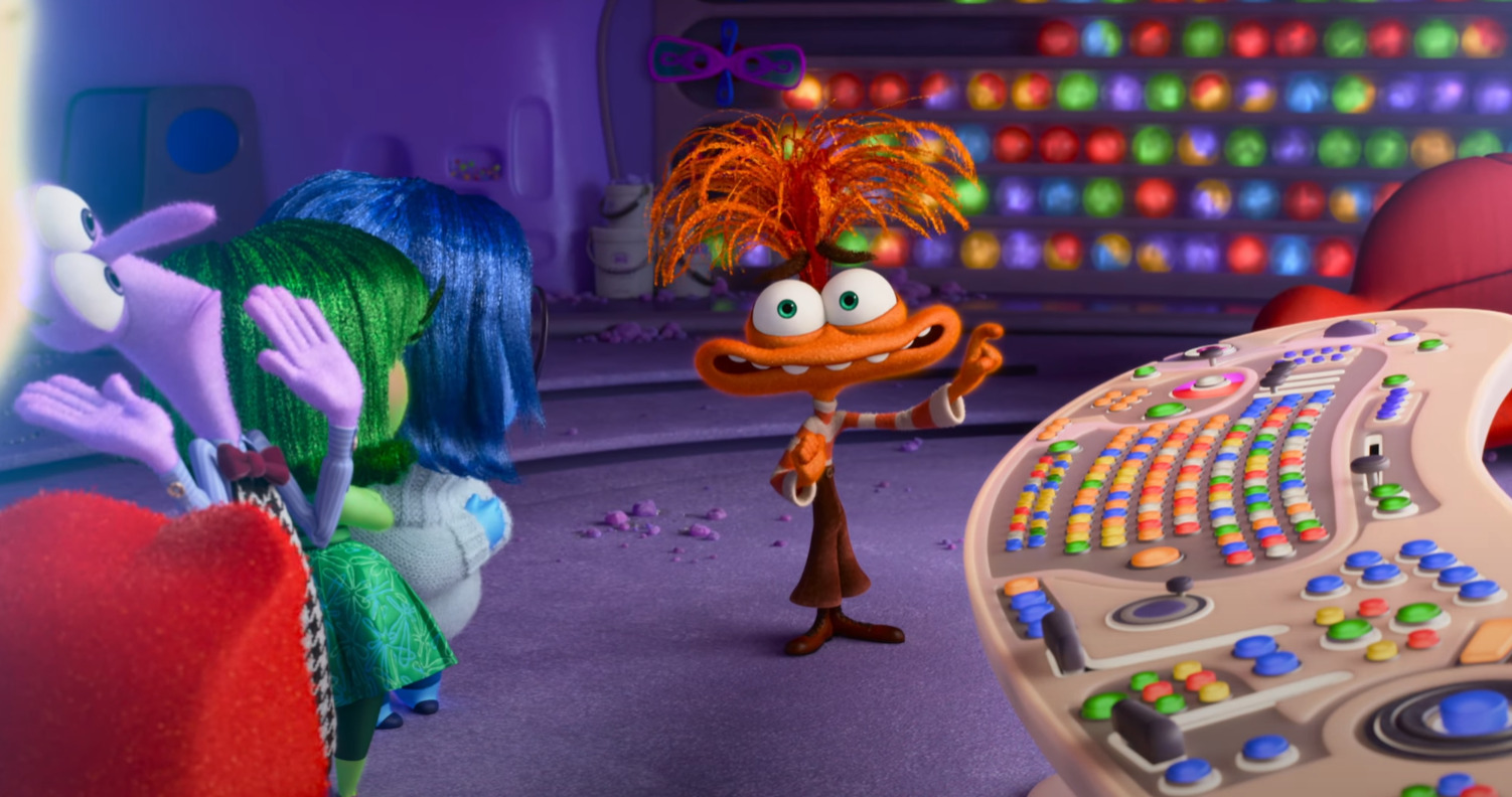 Anxiety, an orange cartoon character, about to push buttons on a control panel in Inside Out 2