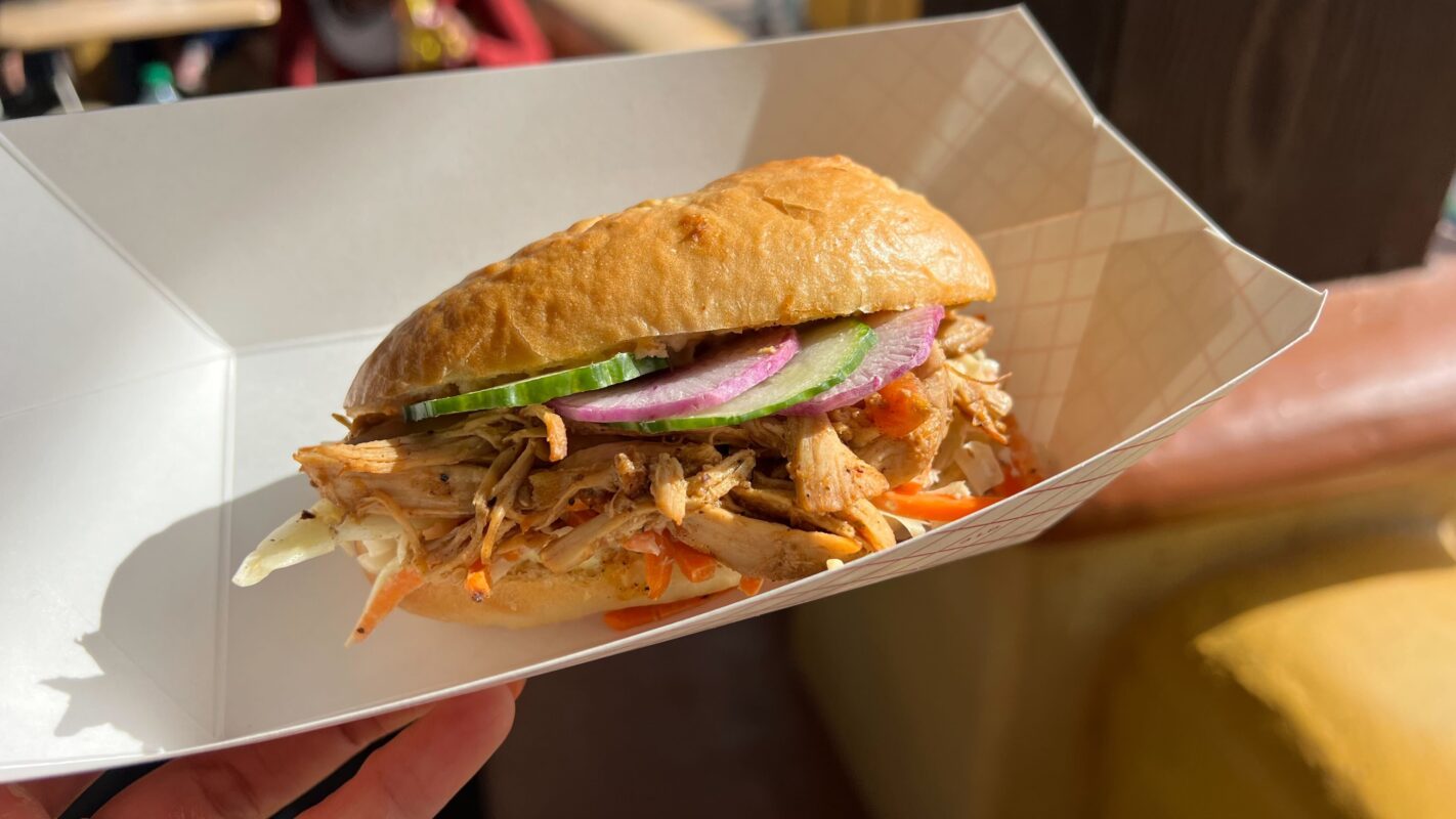 Enjoy a pulled pork sandwich at Sonoma Terrace, served with cucumbers, red onions, and shredded vegetables in a paper tray.