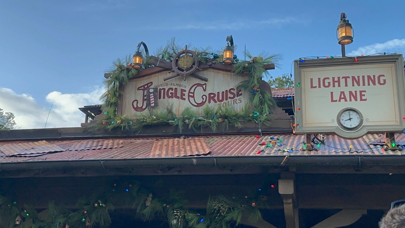 Rustic building adorned with festive holiday decorations, proudly displaying a "Jingle Cruise" sign and featuring a "Lightning Lane" marker complete with a clock.