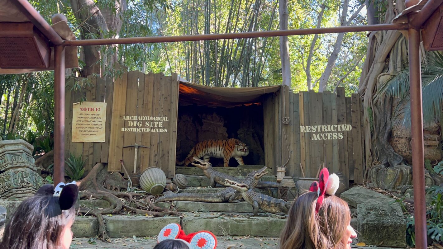 Tiger audio-animatronic framed between wooden fences with scrim above it.