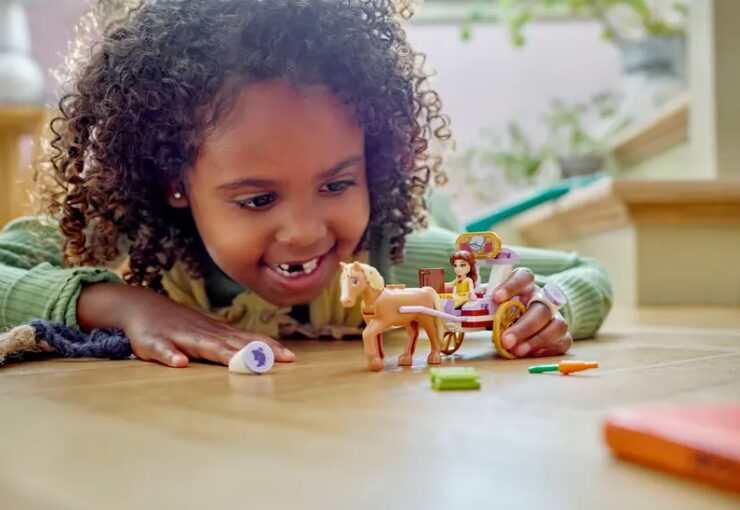A child plays with the Belle's Storytime Horse Carriage LEGO set.