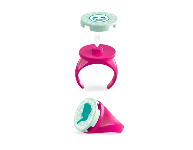 A pink LEGO ring with two icy blue interchangeable decorations. One features an icon of a Snowgie, and the other includes a cameo of Elsa.