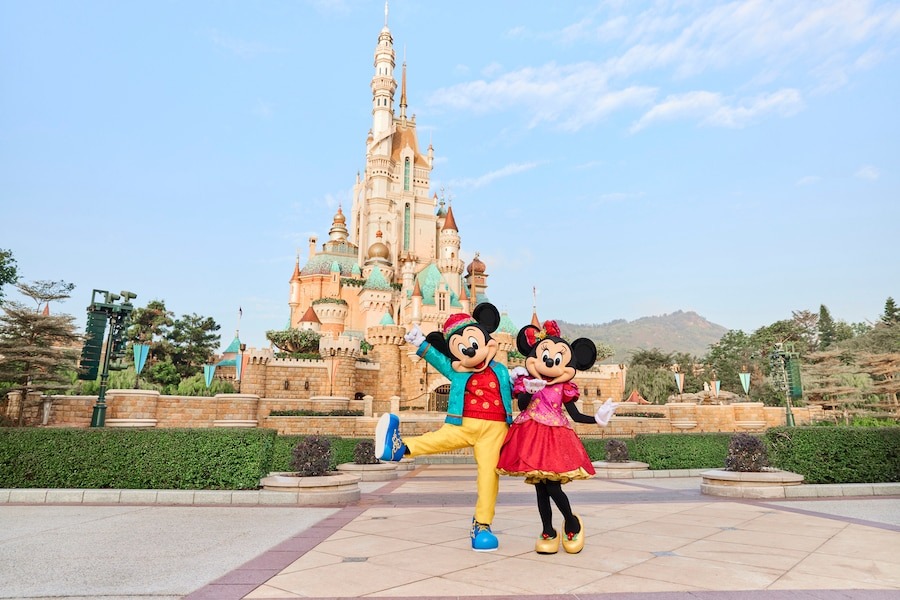 Mickey and Minnie wearing their Chinese New Year outfits in front of the Castle of Magical Dreams.