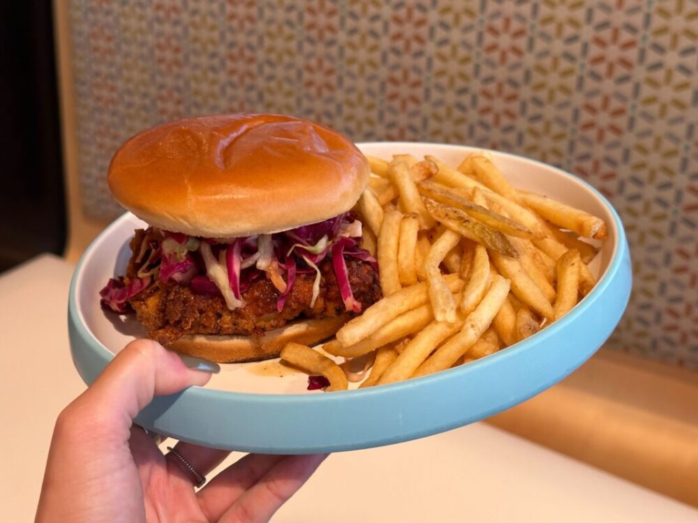 A wide shot of a plate with the Hot Honey Chicken Sandwich and french fries.