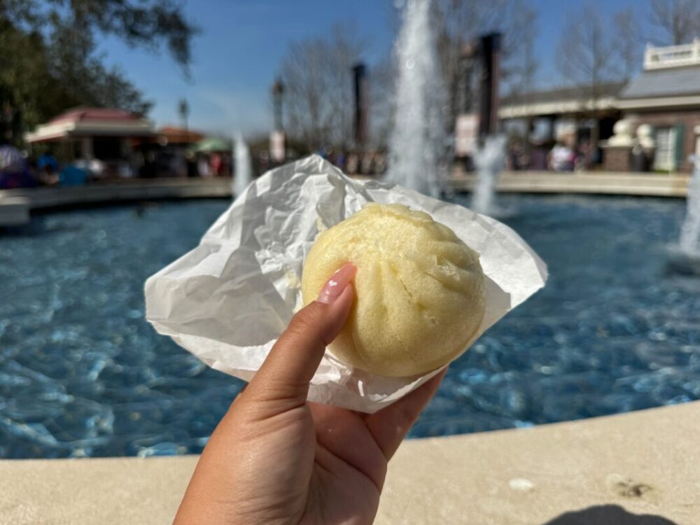 A beige steamed bun on a white paper wrapper.