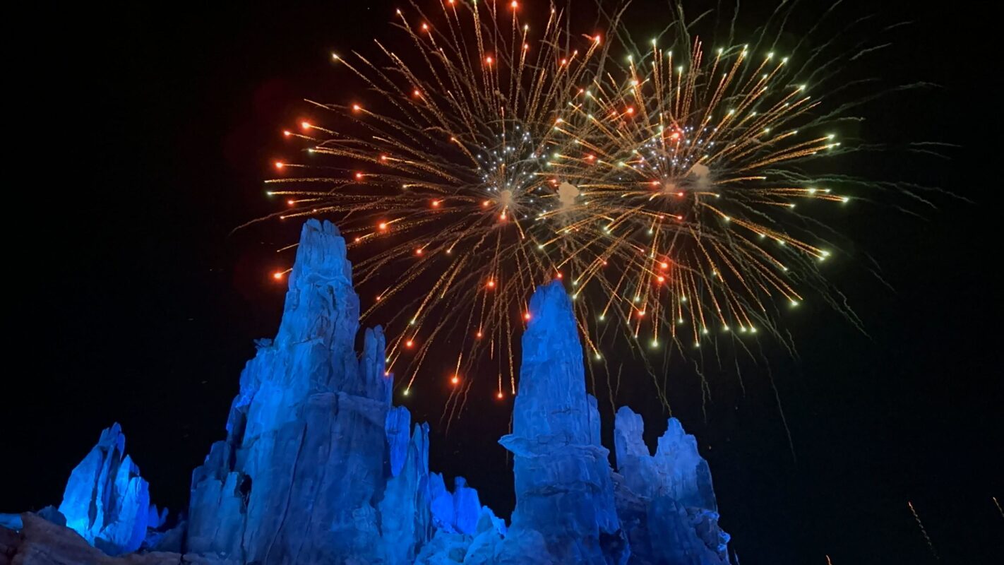 Orange fireworks above Star Wars: Galaxy's Edge spires lit blue
