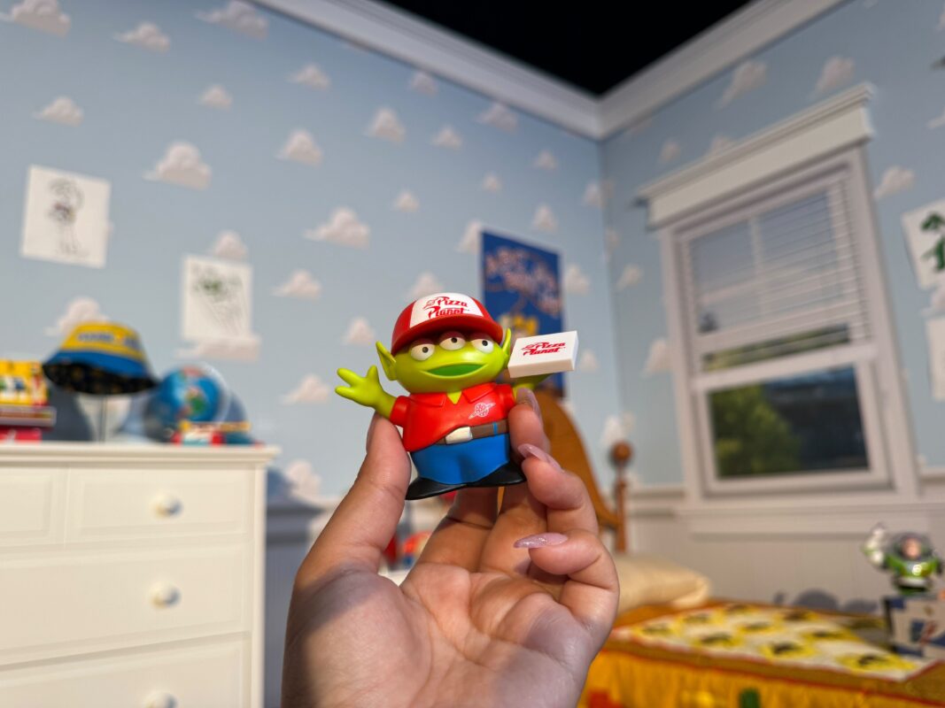 A reporter's hand holding the Green Alien Pizza Planet delivery person figure.