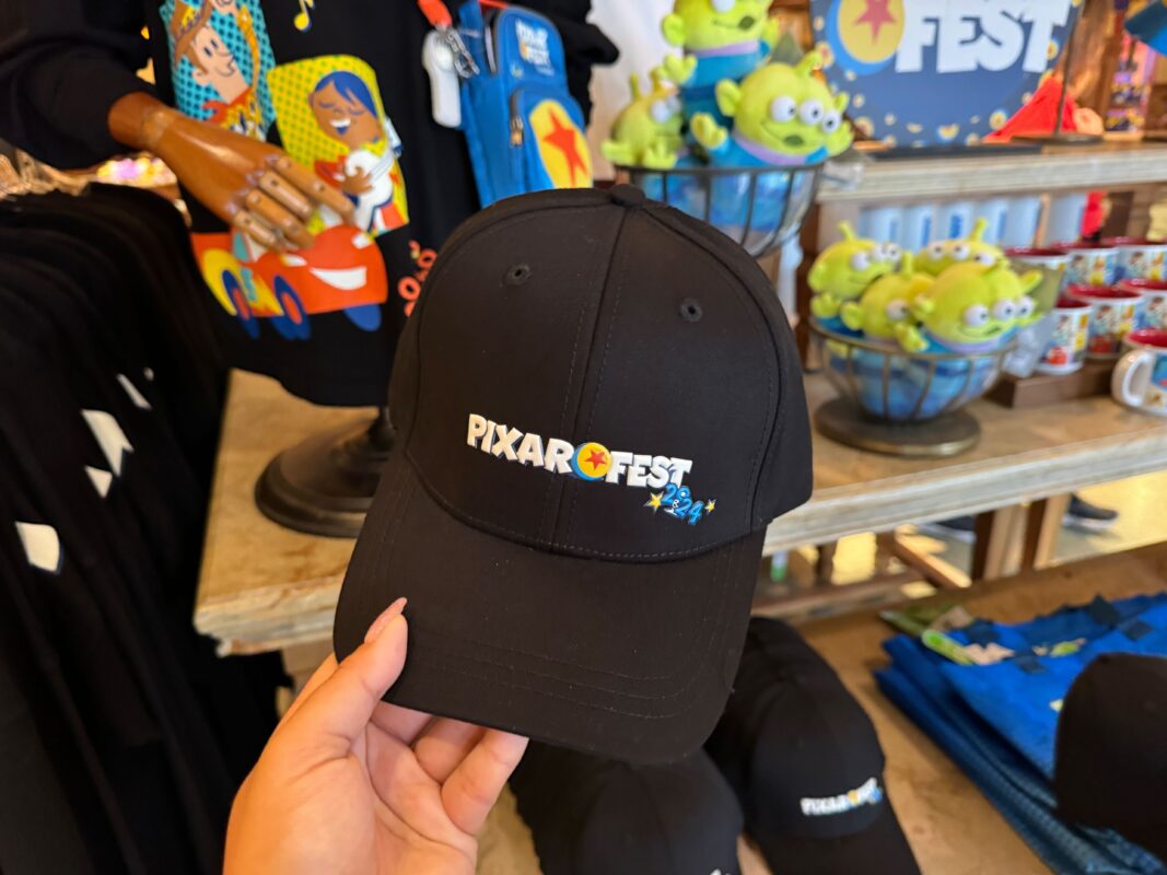 A reporter's hand holding a Pixar Fest ball cap.