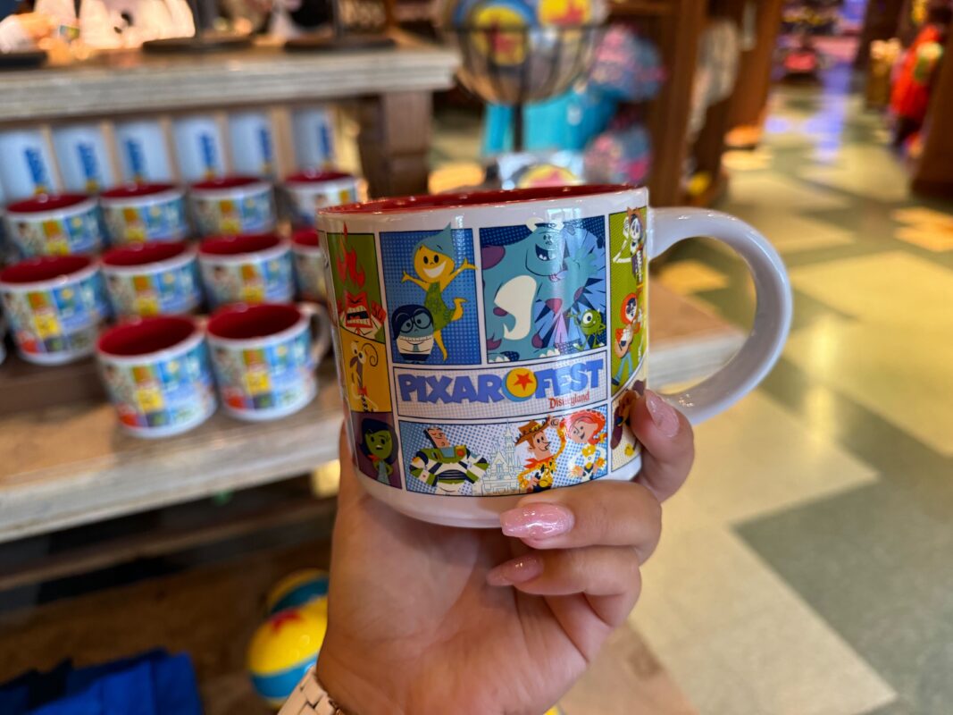 A reporter's hand showing the other side of the Pixar Fest mug.