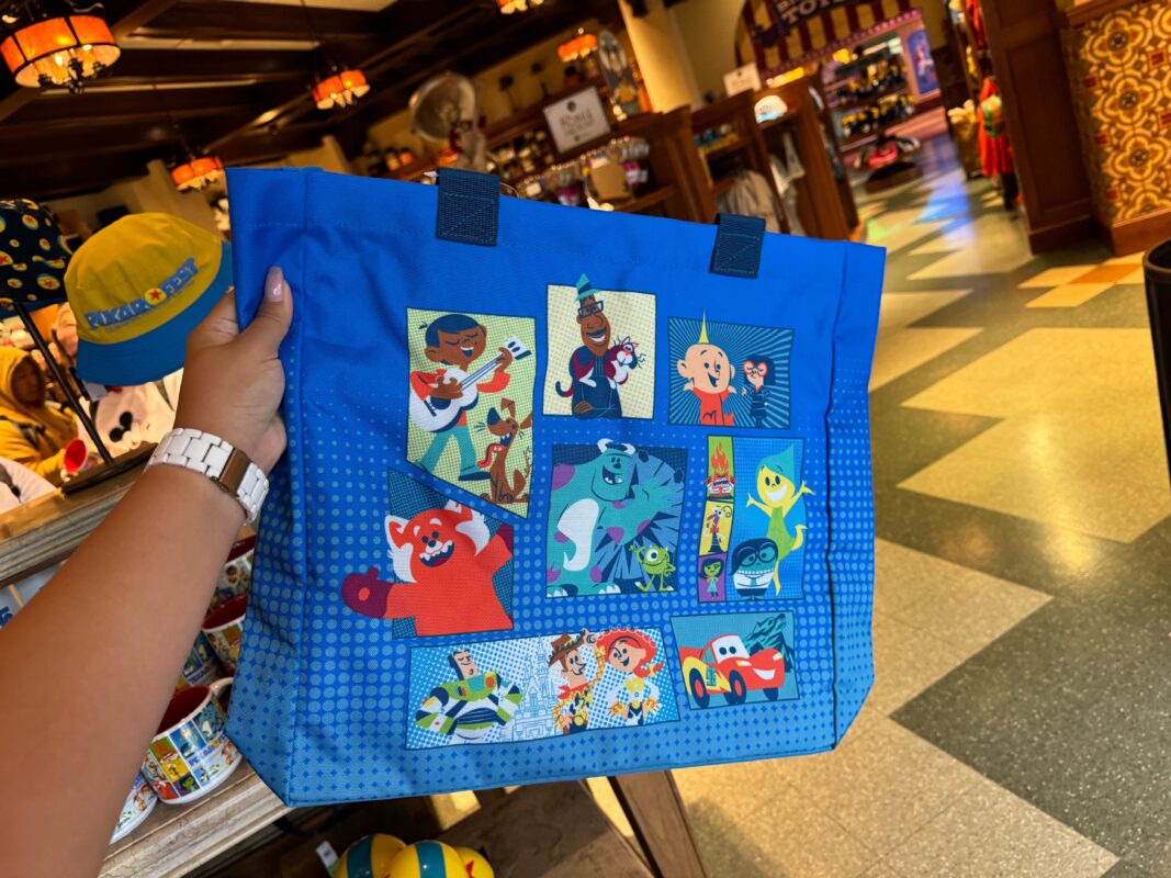 A reporter's hand holding a Pixar Fest tote.