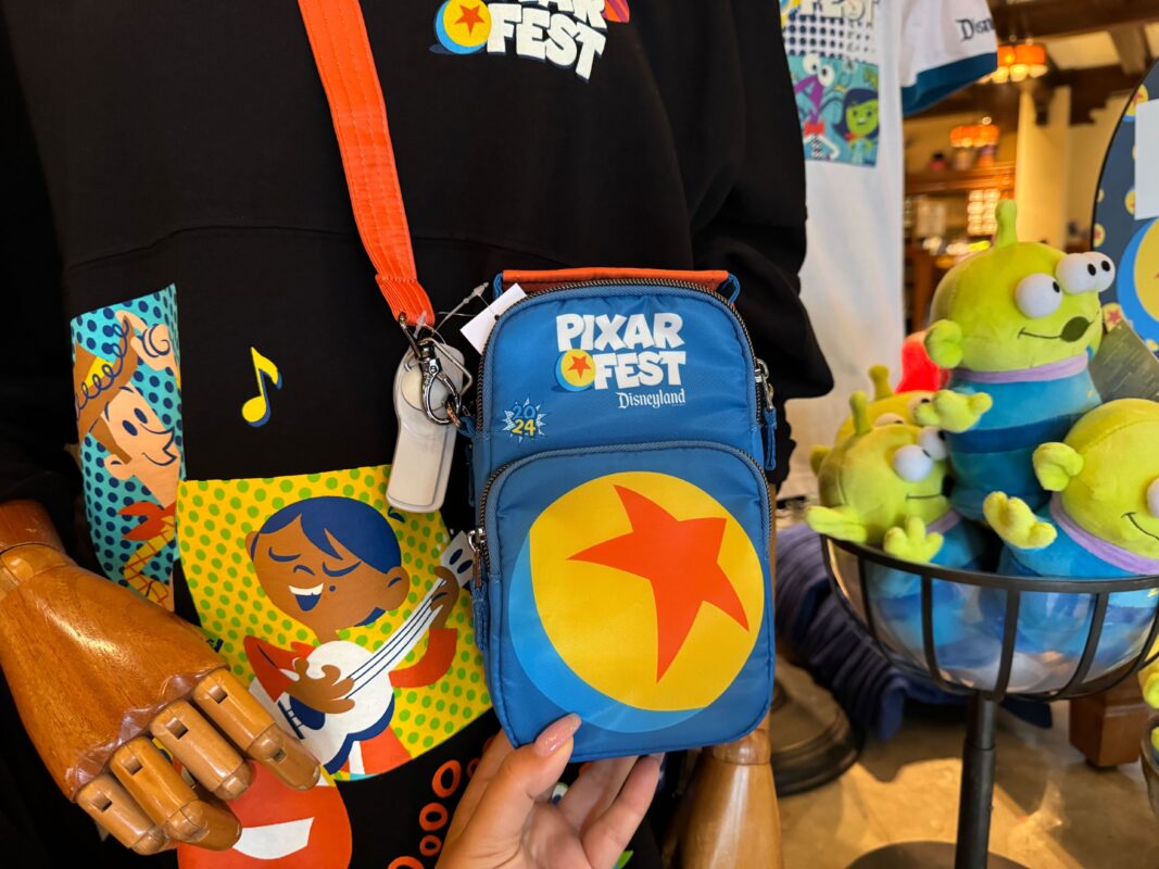 A reporter's hand holding the Pixar Fest Lug crossbody bag.