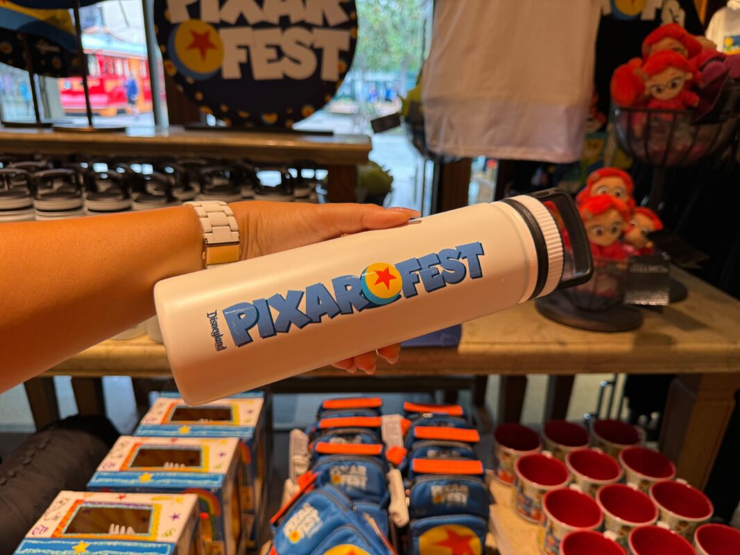 A reporter's hand holding a Pixar Fest water bottle.