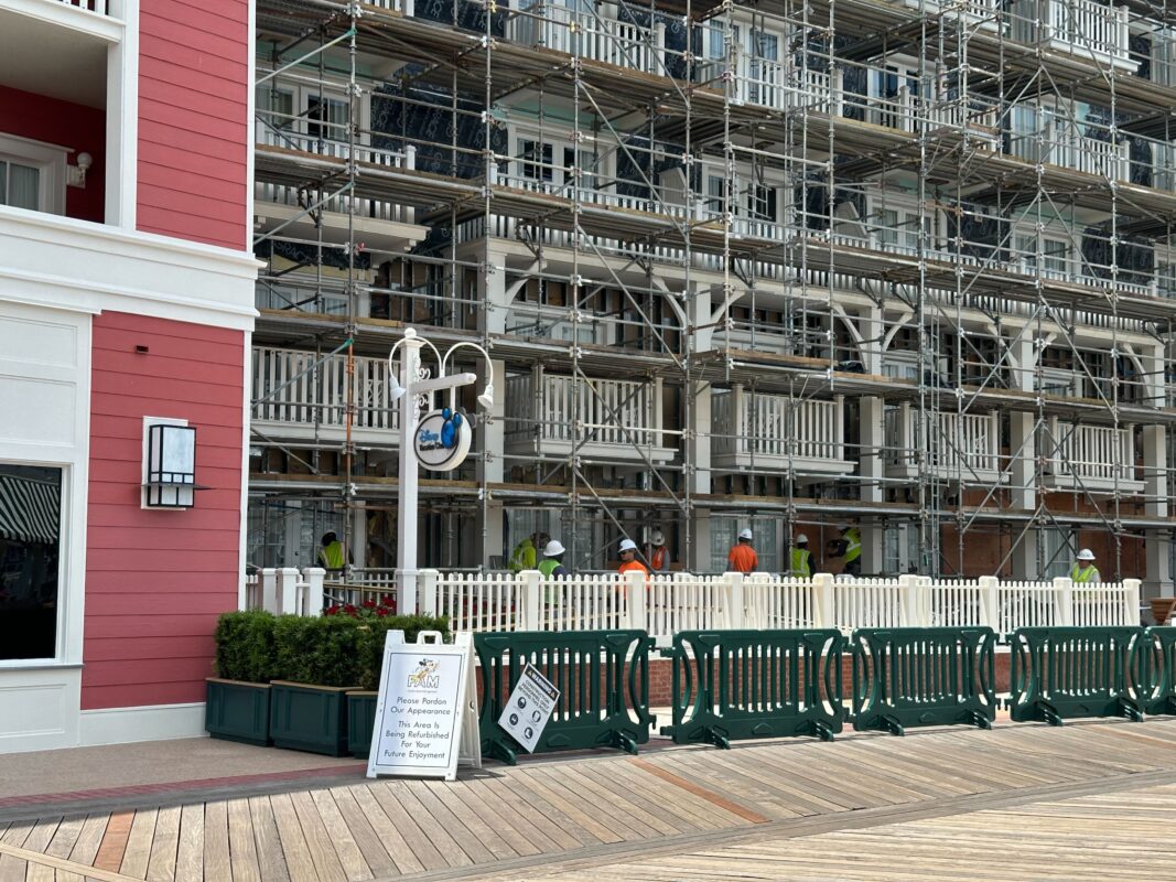 DVC showroom sign with fencing and planters around it, crew members working on facade