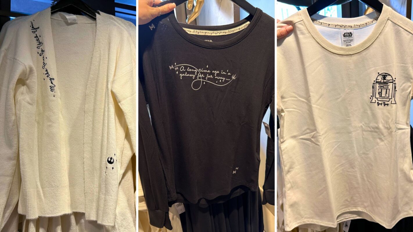 Three hanging shirts: a white one with script, a black one with a quote, and a white one with a printed graphic design.