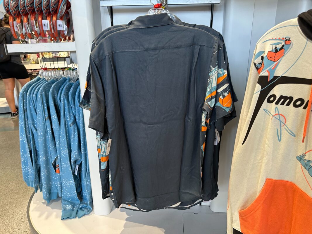 Shirts on display in a store include a black shirt with a rocket design and blue shirts with a star pattern, perfectly paired with the vibrant Tomorrowland ear headband.