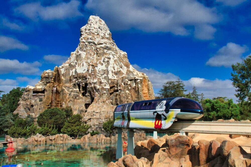 The Matterhorn Bobsleds mountain facade with a Monorail train driving by on an elevated track