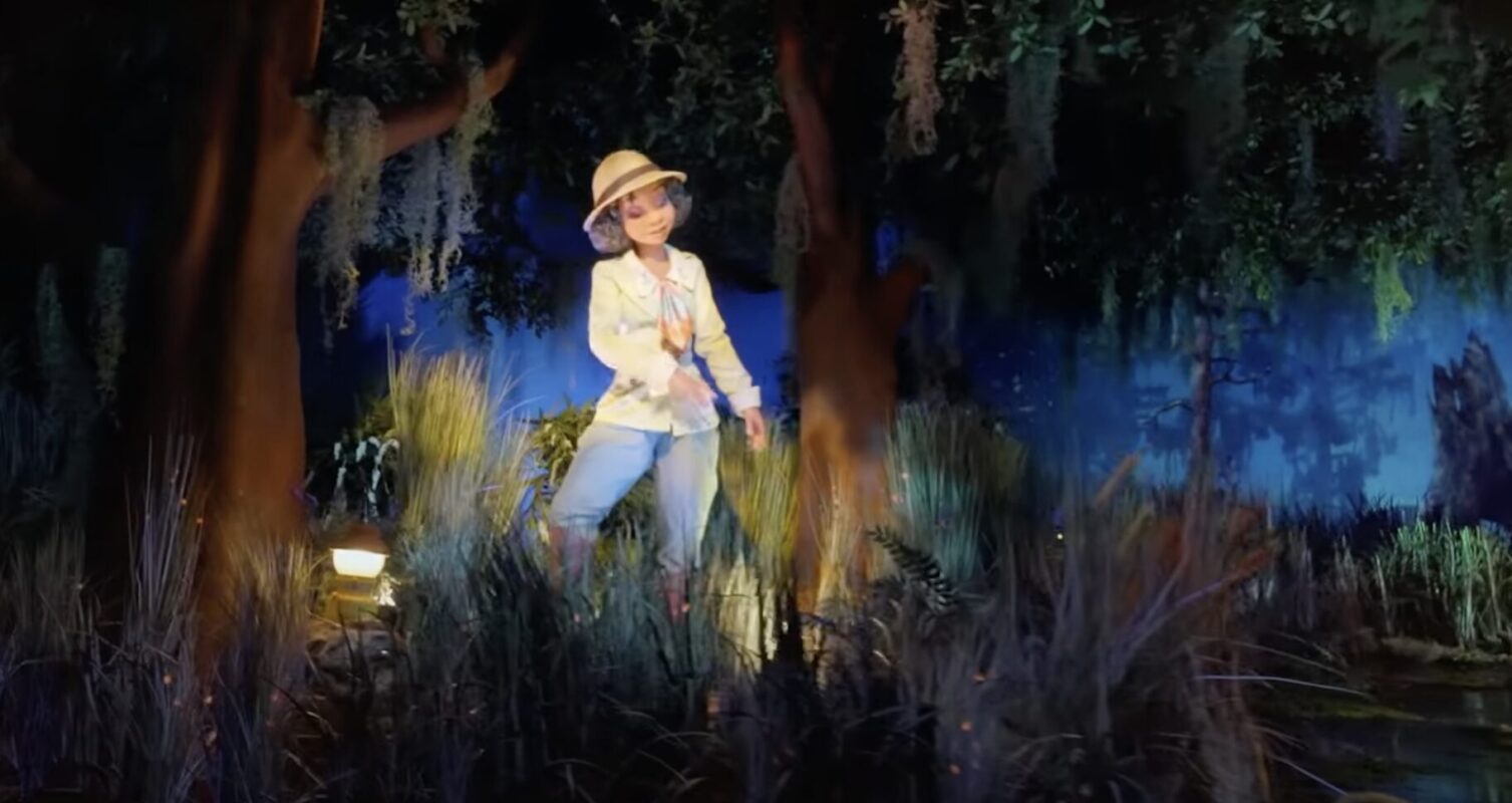 A person, wearing a hat and white shirt, stands in a wooded area surrounded by tall grasses under a blue sky—capturing the essence of what we call imagineering.