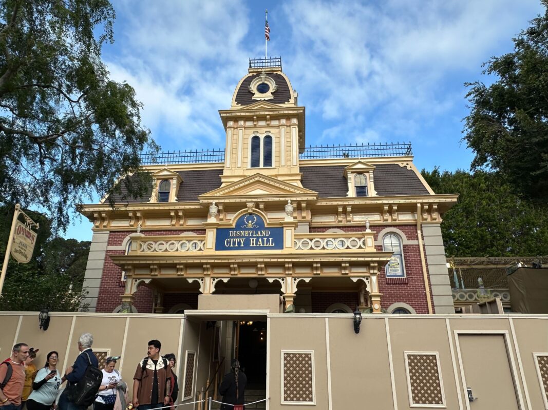 Disneyland city hall building with visitors and construction barriers under a blue sky with clouds.