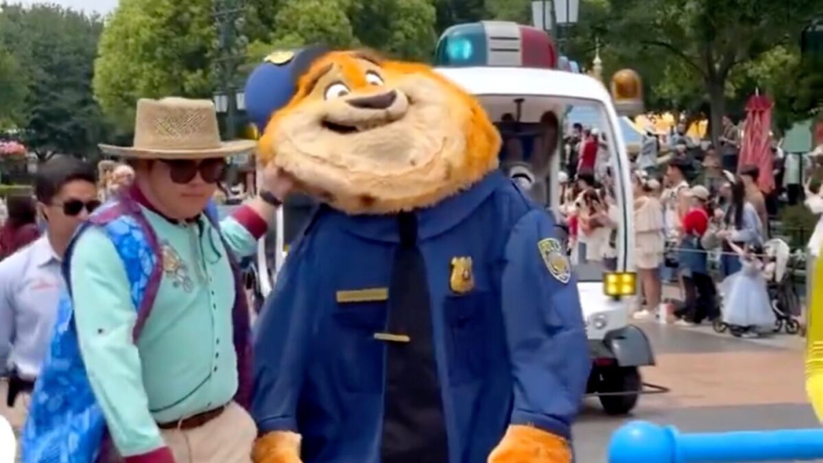 A deflated costumed Clawhauser character being escorted by a Cast Member away from the Zootopia pre-parade