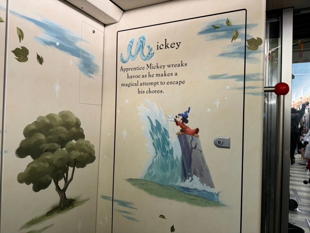 Interior of a train with doors decorated with an illustration of apprentice mickey from fantasia, controlling water, with descriptive text about the scene.