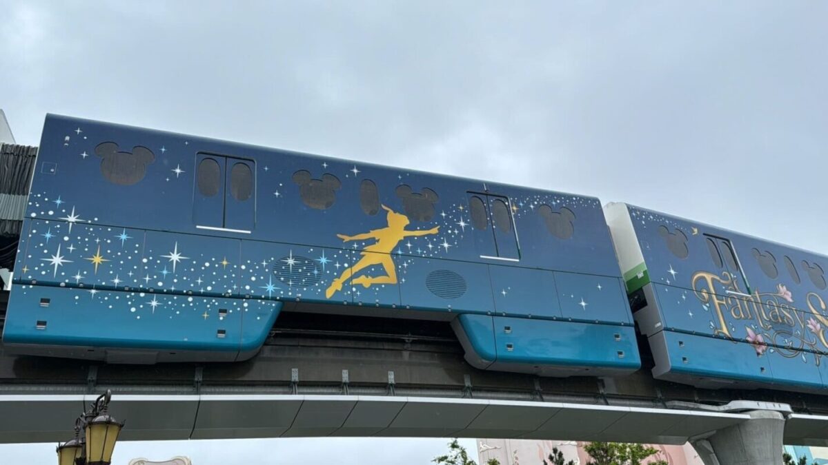 Blue monorail with mickey mouse silhouettes and a yellow peter pan silhouette against a cloudy sky.