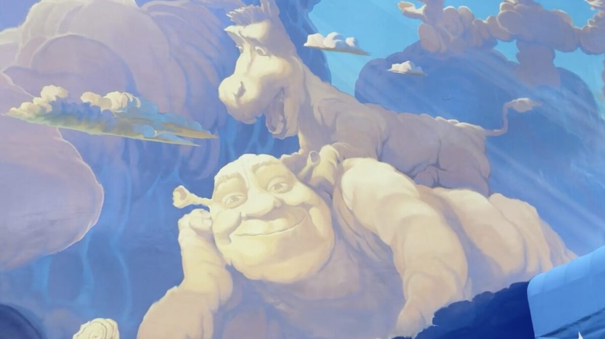 A mural depicts cloud formations resembling two cheerful animated characters, one a donkey and the other a green ogre, against a blue sky with scattered clouds.