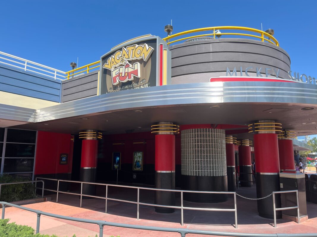 Entrance to a building with a curved facade, featuring a sign that reads "Vacation Fun" above the door. The exterior is modern with red pillars and yellow railings.