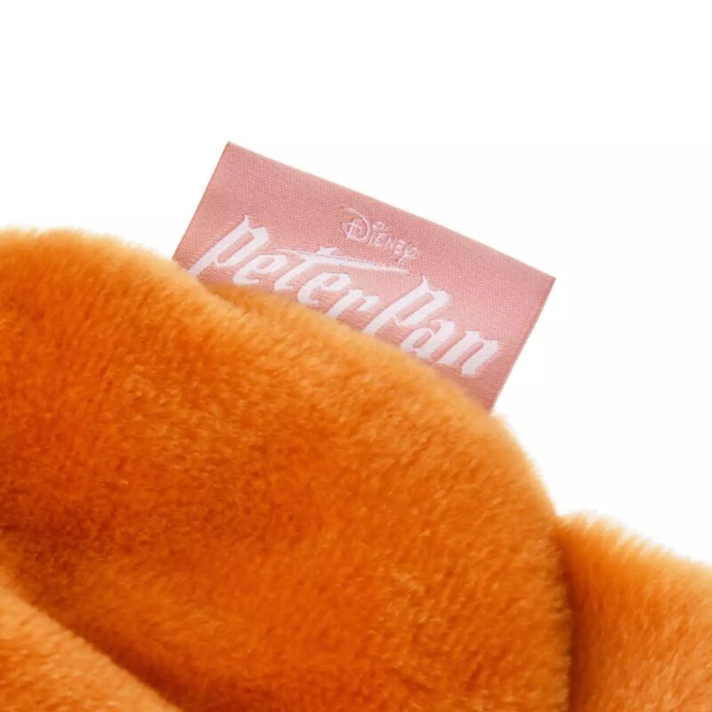 Close-up of an orange fuzzy fabric with a pink "Disney Peter Pan" tag attached.
