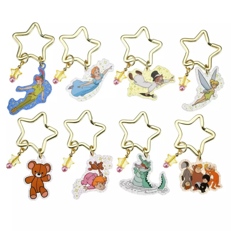 Eight star-shaped keychains feature characters from the animated Peter Pan series, including Peter Pan, Wendy, Tinker Bell, and others. Each keychain has a small bell and a pearl bead attached.
