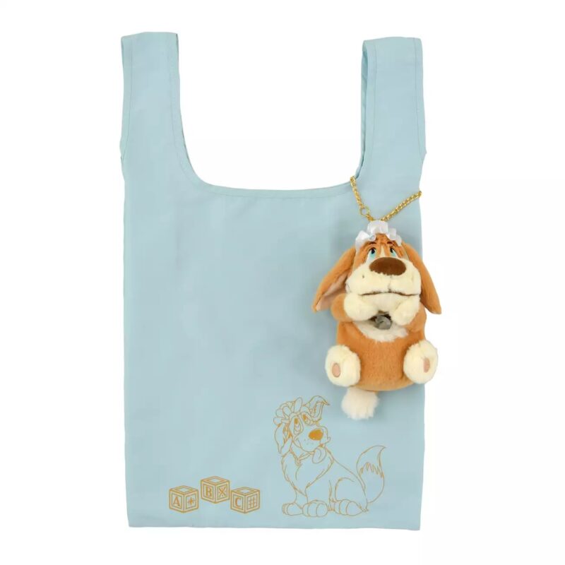 Light blue reusable bag with an illustrated dog sitting near alphabet blocks. A small plush dog keychain is attached to the bag handle.