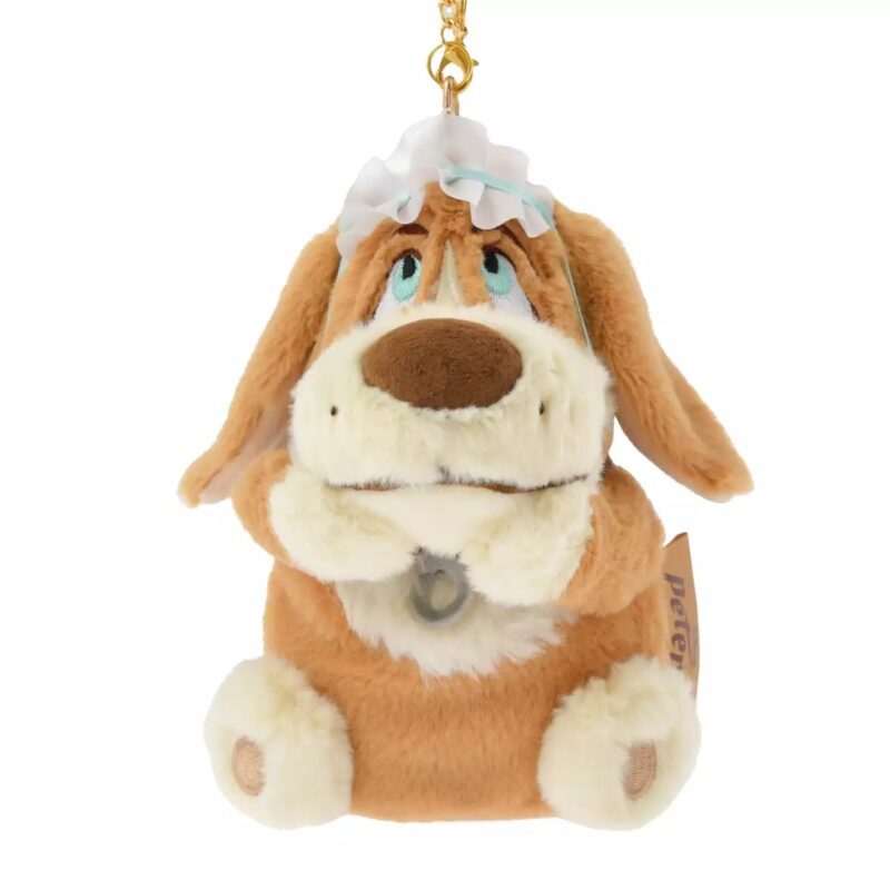 A plush keychain depicting a tan and brown dog with long ears, wearing a frilly white bonnet. The dog has expressive blue eyes and a small bell attached to its neck.
