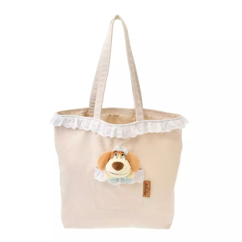 A beige tote bag with lace trim and a front pocket adorned with a small plush dog face.