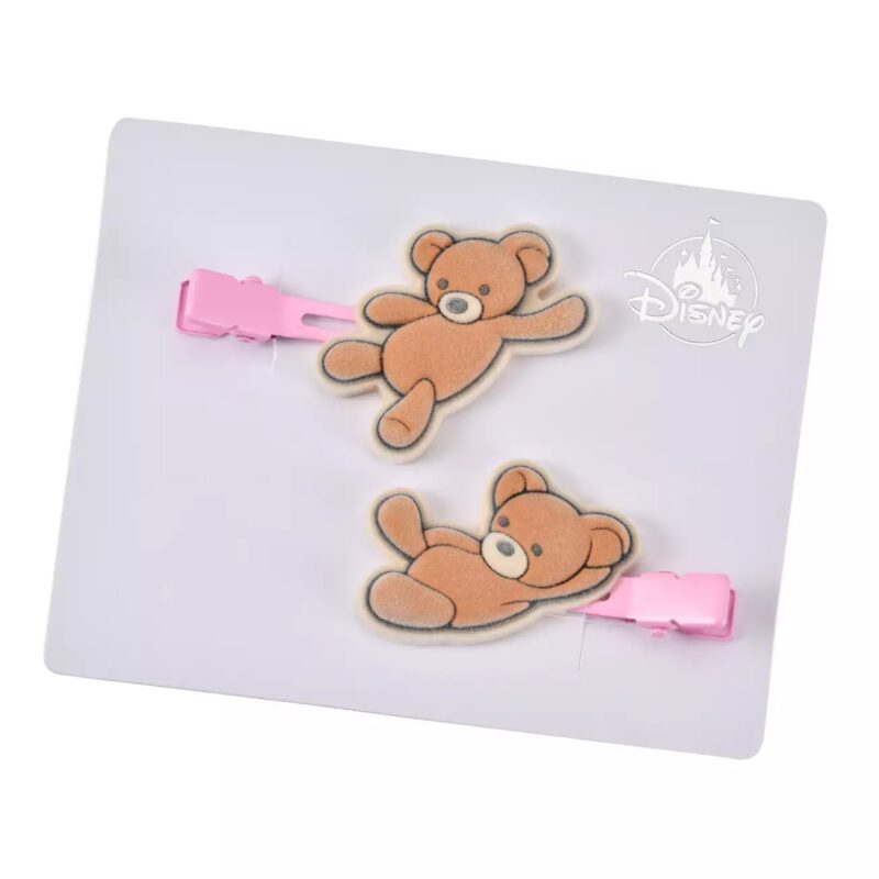 A pair of pink hair clips featuring teddy bear designs, displayed on a card with the Disney logo on the top right corner.