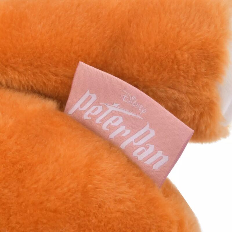 Close-up of an orange furry object with a pink label that has the text "Disney Peter Pan" printed on it.