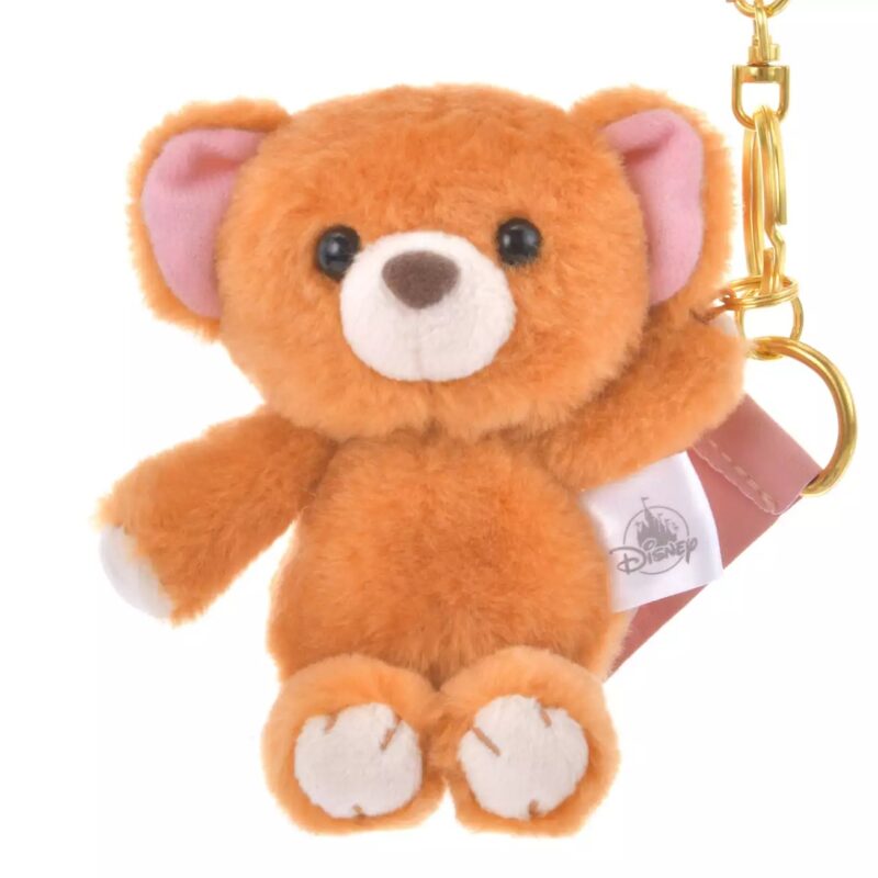 A small, plush orange teddy bear keychain with a golden clip, featuring pink ears and a tag with the Disney logo.
