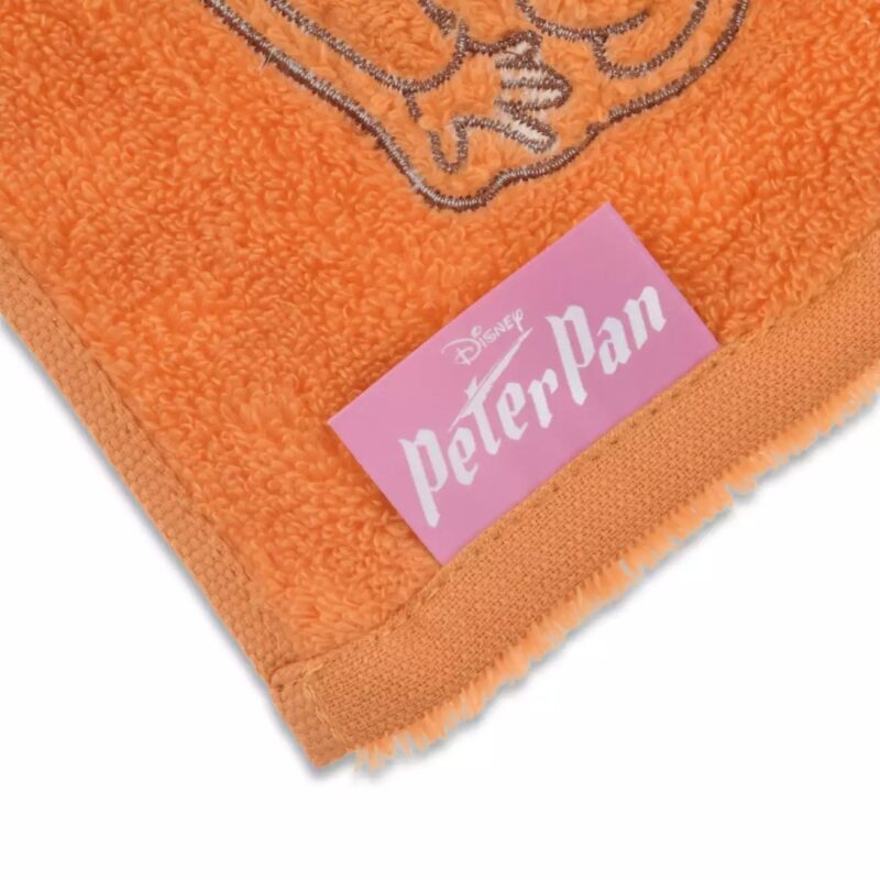 Close-up of an orange towel with an embroidered character and a pink label that reads "Disney Peter Pan.